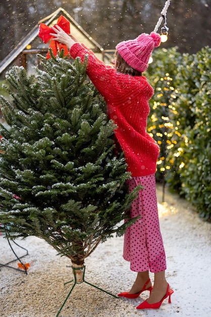 Mujer decora el árbol de Navidad en Bacyard