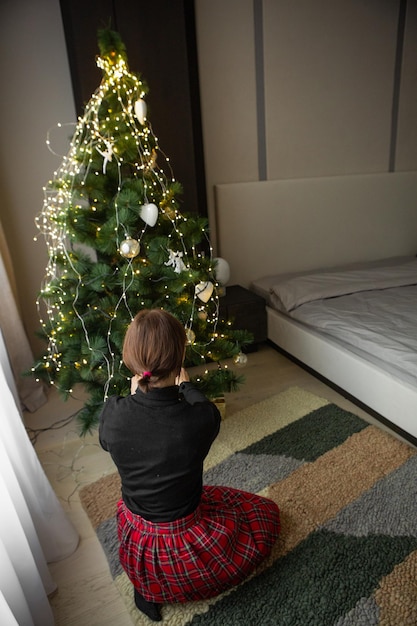 Mujer decora la cama del árbol de navidad esperando vacaciones