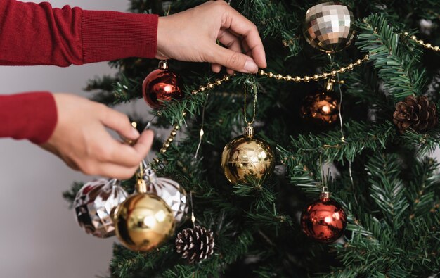 Mujer decorando un árbol de Navidad con adornos en el día de Navidad