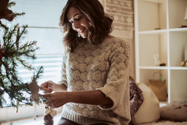 Mujer decorando el árbol de Navidad en casa - Temporada de invierno