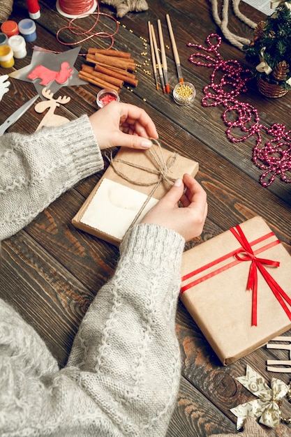 Mujer decorando caja con regalos de Navidad