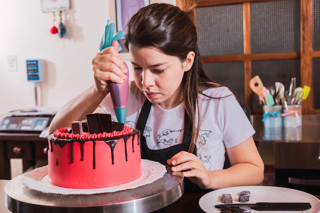 Mujer decorando tarta de chocolate en la cocina.