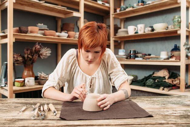 Mujer decorar cuenco de barro en el taller de alfarero