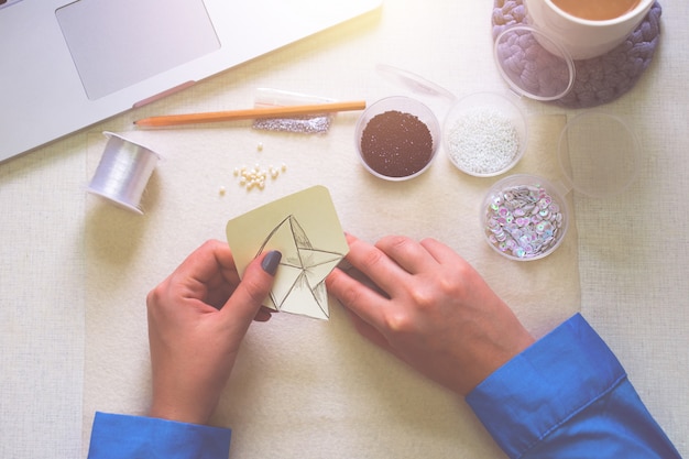 Foto la mujer se dedica a la actividad creativa. haciendo broche. lay flat