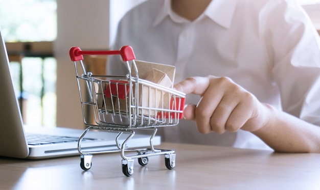 Mujer dedo índice empujando carrito de compras pequeño con concepto de compras en línea de Internet