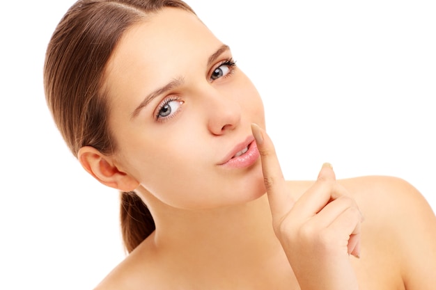 Mujer con un dedo en los labios sobre fondo blanco.