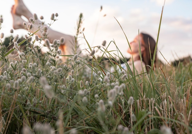 Mujer Defocused descansando en el campo de verano o prado con hierba verde disfrutando de la vida lenta en la naturaleza