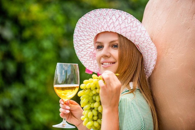 Mujer degustando vino en un viñedo Ella está mostrando una copa de vino Mujer sosteniendo una copa de vino blanco en un viñedo Ella está mostrando uvas Degustación de vinos en una bodega al aire libre Elaboración de uvas y vinos