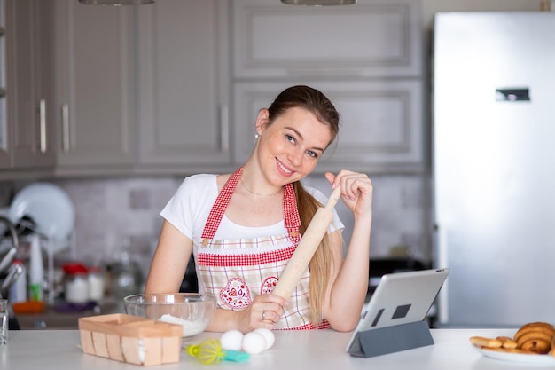 Mujer en delantal con rodillo en la cocina