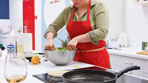 Mujer con delantal rojo cocinando en una cocina blanca