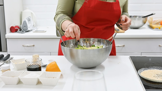 Mujer con delantal rojo cocinando en una cocina blanca