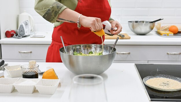 Mujer con delantal rojo cocinando en una cocina blanca