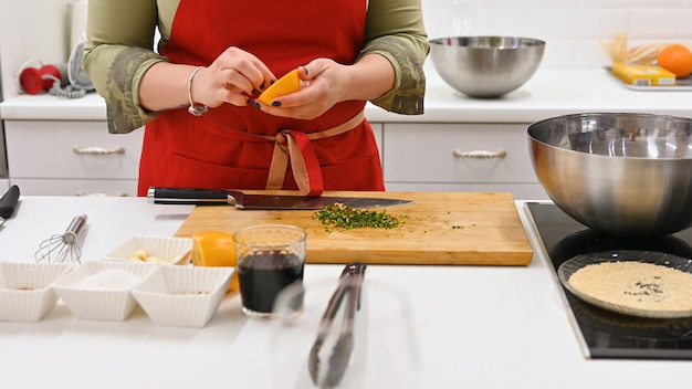 Mujer con delantal rojo cocinando en una cocina blanca