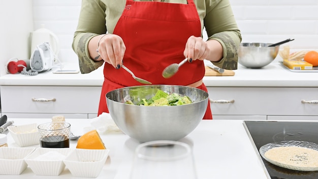 Mujer con delantal rojo cocinando en una cocina blanca