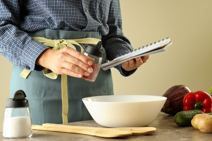 Foto una mujer en un delantal tiene un libro de recetas y especias y cocineros