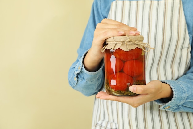 Mujer en delantal tiene tarro de tomates en escabeche