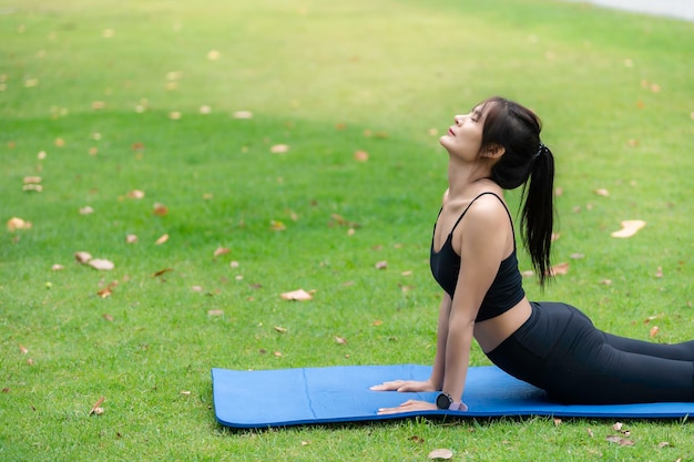 Mujer delgada asiática hace ejercicio sola en el parque Cansada del concepto de yoga de entrenamiento