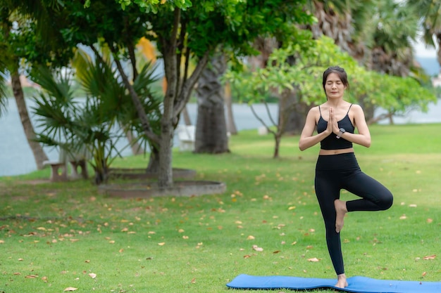 Una mujer delgada asiática hace ejercicio sola en el parque Cansada del entrenamiento Juega el concepto de yoga