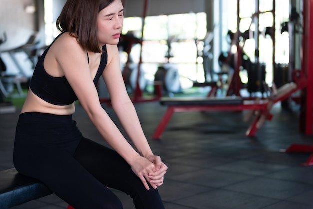 Mujer delgada asiática juega fitness en el gimnasioElla siente dolor por el ejercicio