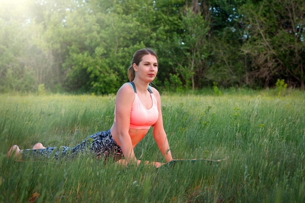 Mujer delgada atractiva joven en ropa deportiva que se extiende en el parque Concepto de estilo de vida saludable