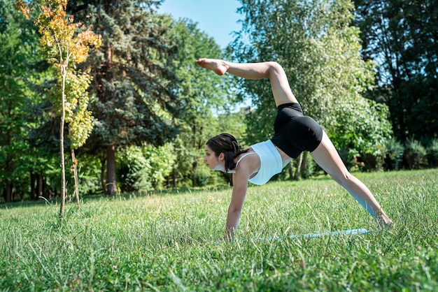 Mujer delgada y bonita practicando yoga relajante o pilates en la naturaleza