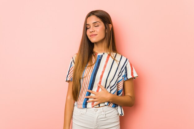 La mujer delgada joven toca la panza, sonríe suavemente, comiendo y concepto de la satisfacción.