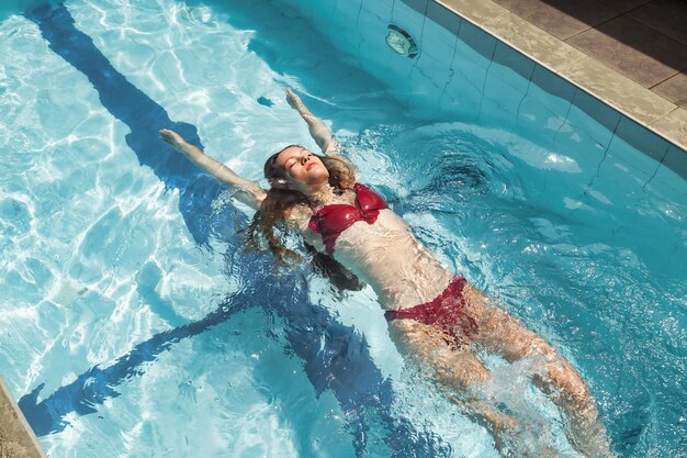 Mujer delgada joven en traje de baño relajante junto a la piscina