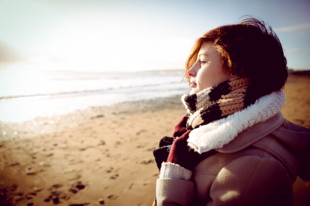 Mujer delgada mirando el mar durante la puesta de sol