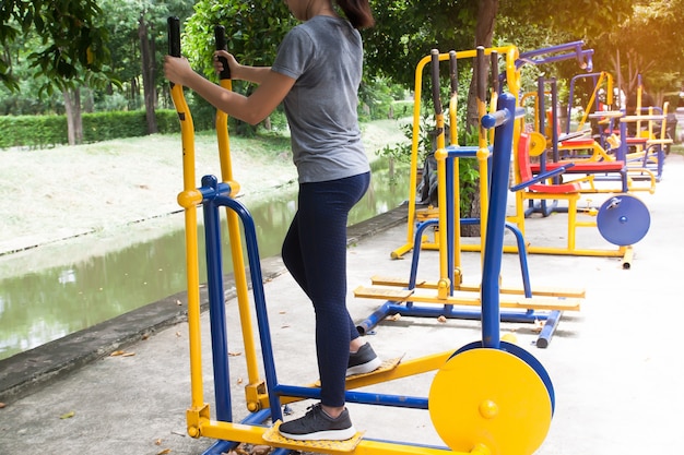 Mujer delgada que ejercita en el equipo de entrenamiento en el parque