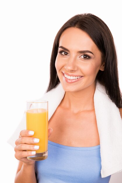 Mujer delgada con toalla sosteniendo un vaso de jugo de naranja