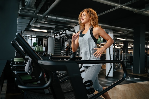 Mujer delgada trotar en una cinta en un gimnasio interior se dedica al concepto de fitness de una vida sana ...