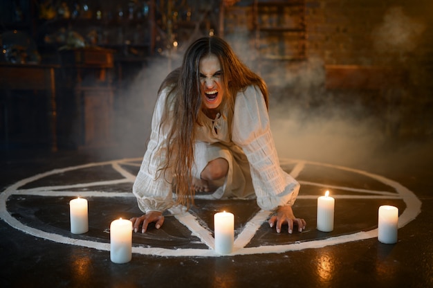 Mujer demoníaca loca sentada en círculo mágico con velas, demonios echando. Exorcismo, ritual misterioso paranormal, religión oscura, horror nocturno, pociones en el estante