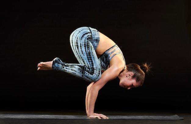 Mujer demostrando una pose de cuervo en yoga