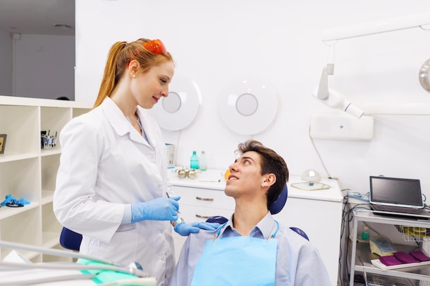 Mujer dentista apoyando al paciente masculino