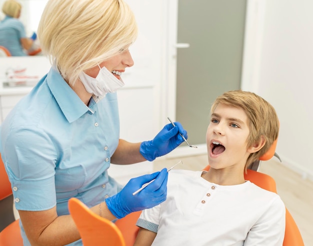 Mujer dentista cuidadosa examinando los dientes de los niños
