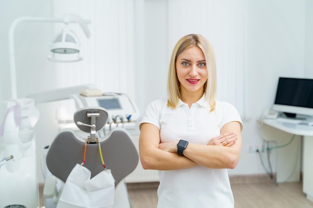 Mujer dentista está planteando en la clínica de estomatología moderna. Instrumento estomatológico y sillón en la clínica odontológica.