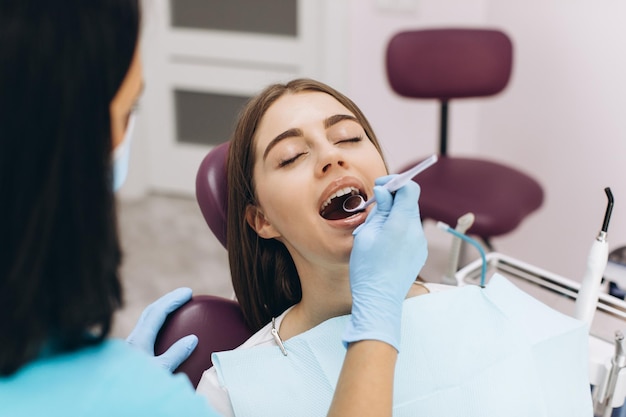 Mujer dentista examina a su paciente en un sillón dental