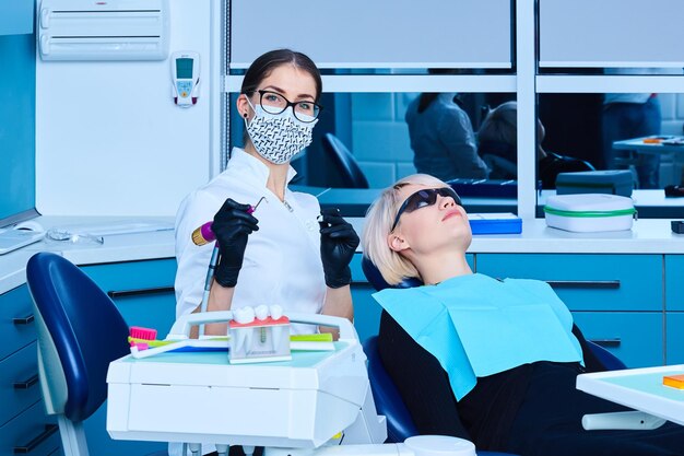 Mujer dentista examinando a un paciente en el consultorio dental para una mujer