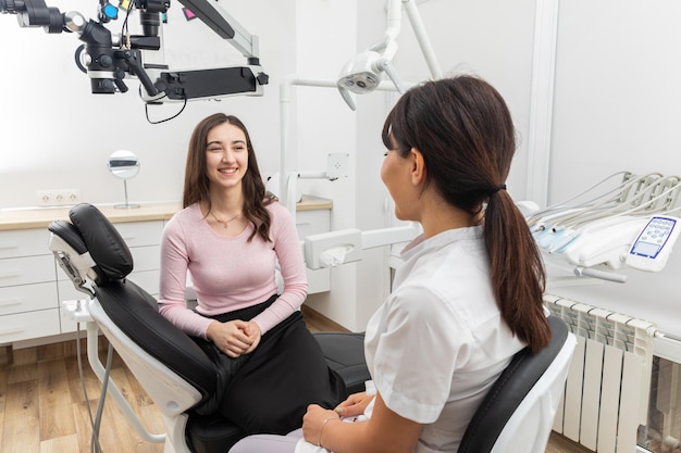 Mujer dentista hablando con un paciente joven durante una cita en una clínica dental moderna antes de los dientes