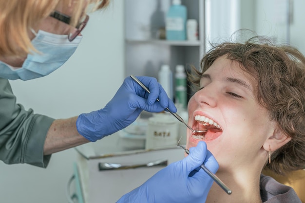 Mujer dentista hace un examen de la cavidad oral del paciente y realiza un tratamiento de caries en odontología