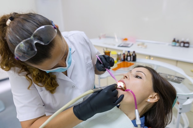 Mujer dentista con lámpara UV de curado dental en los dientes