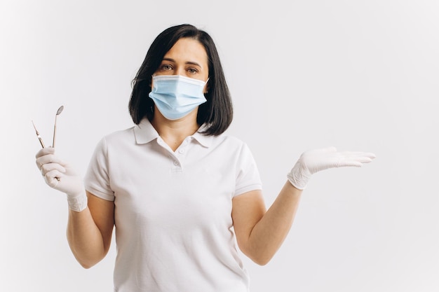 Foto mujer dentista con una máscara médica muestra algo en un espacio de copia
