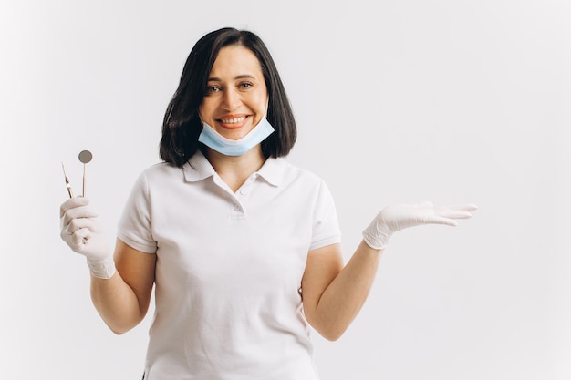 Foto mujer dentista con una máscara médica muestra algo en un espacio de copia