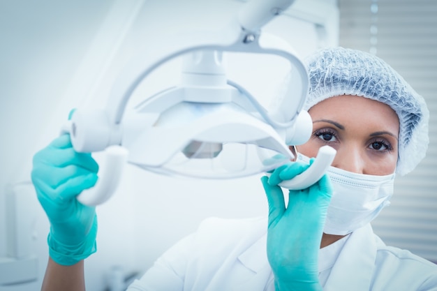 Foto mujer dentista en máscara quirúrgica ajuste de luz