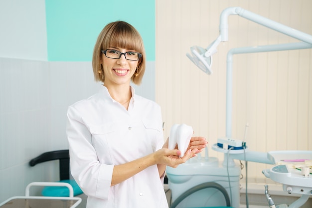 Mujer dentista en oficina sosteniendo la herramienta como concepto de cuidado de la cavidad bucal