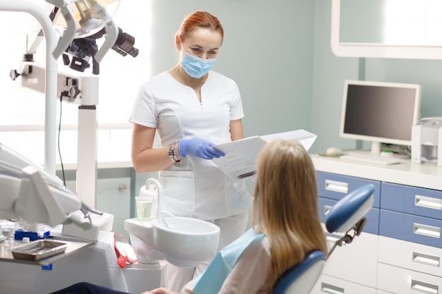 Mujer dentista con paciente mujer hablando en la oficina de la clínica dental