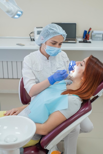 Mujer dentista revisando a su paciente por caries Mujer pelirroja examinada por un médico La niña hará la salud de los dientes