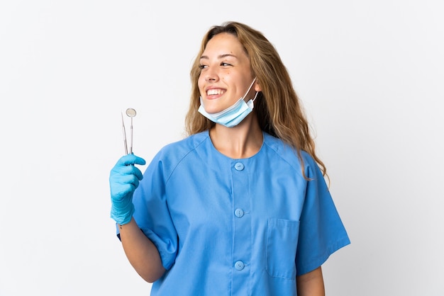 Mujer dentista sosteniendo herramientas aisladas en blanco mirando lateral