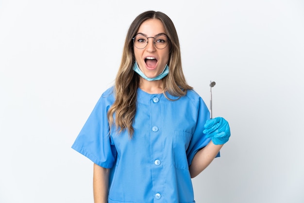 Mujer dentista sosteniendo herramientas posando aislado contra la pared en blanco