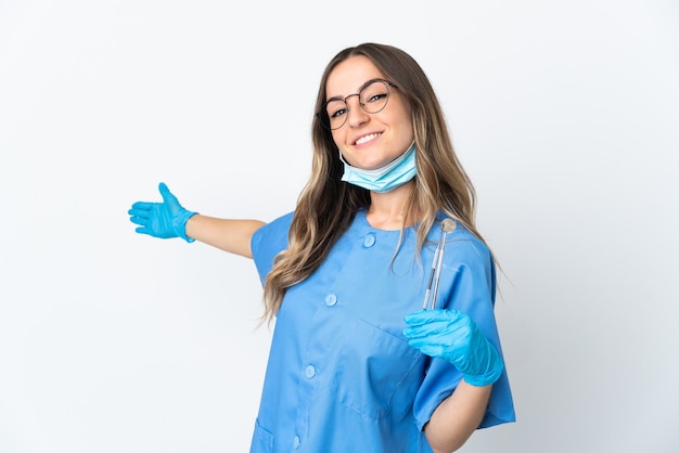 Mujer dentista sosteniendo herramientas posando aislado contra la pared en blanco